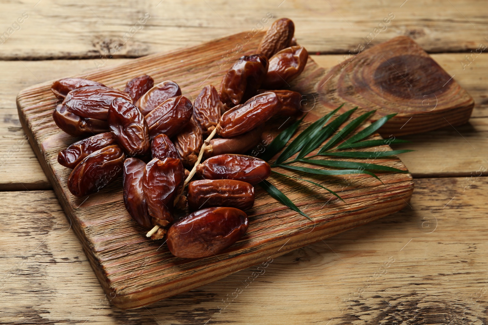 Photo of Tasty sweet dried dates with green leaf on wooden table, closeup