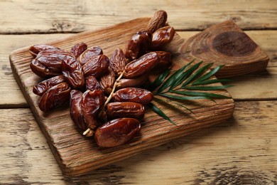 Tasty sweet dried dates with green leaf on wooden table, closeup