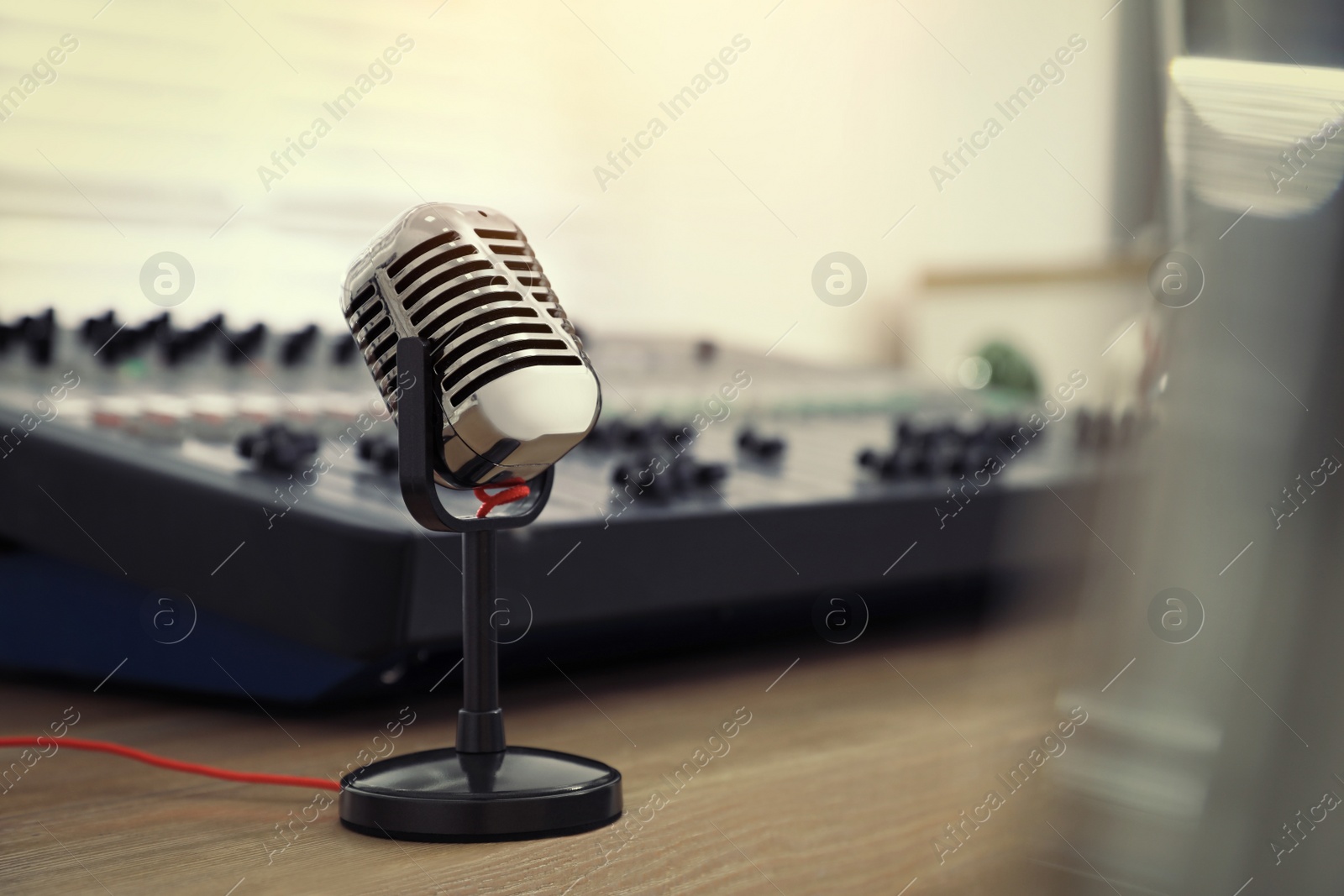 Photo of Microphone and professional mixing console on wooden table in radio studio