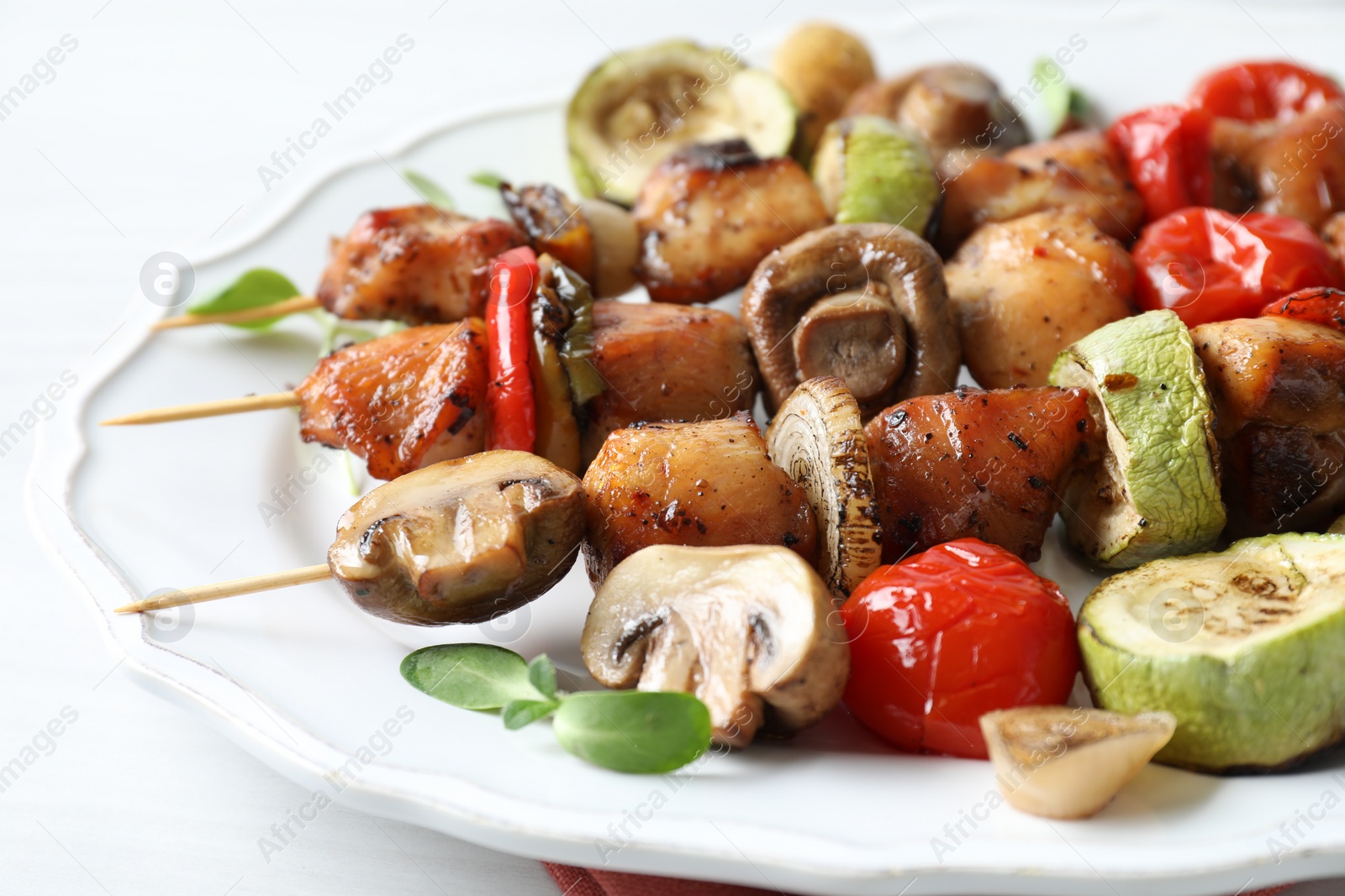 Photo of Delicious shish kebabs with vegetables and microgreens on table, closeup