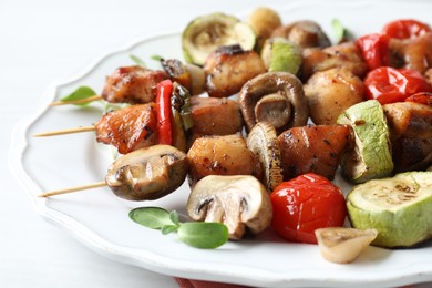 Photo of Delicious shish kebabs with vegetables and microgreens on table, closeup