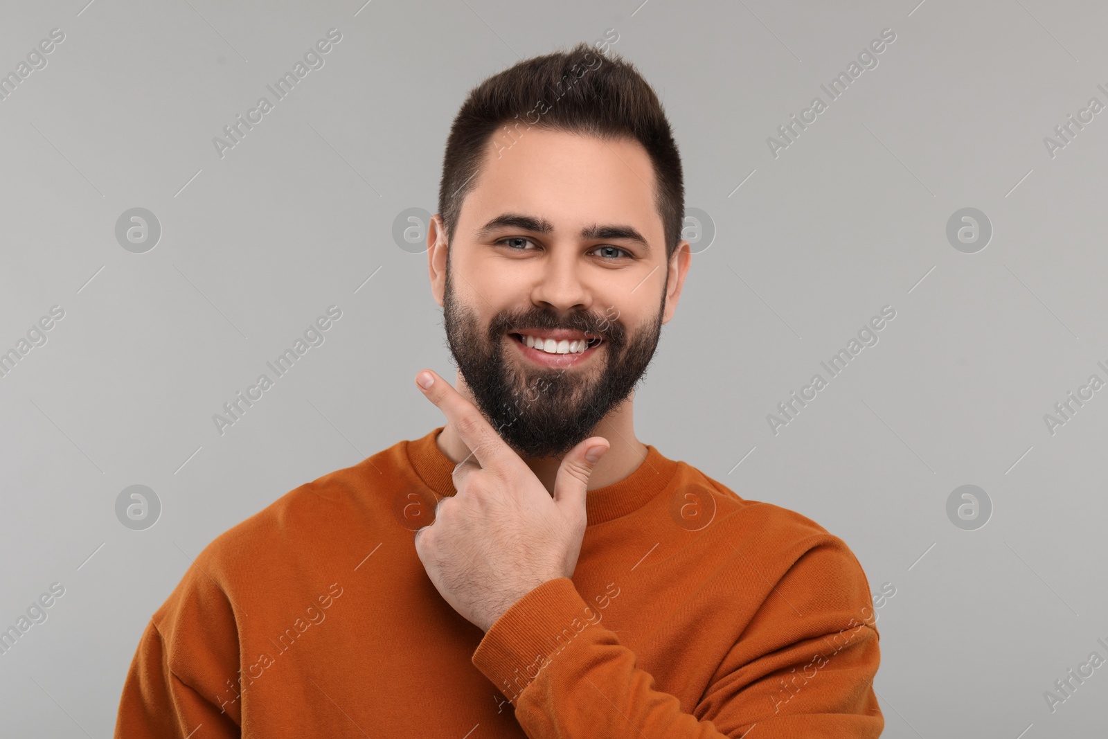 Photo of Man showing his clean teeth and smiling on gray background