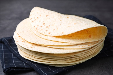Photo of Stack of corn tortillas on table, closeup. Unleavened bread