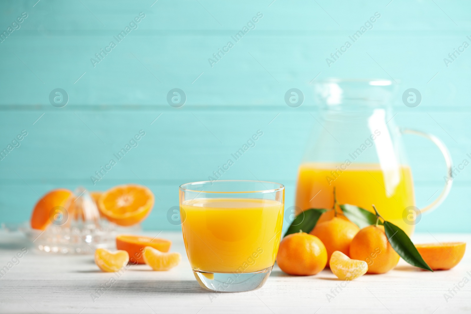 Photo of Glass of fresh tangerine juice and fruits on white wooden table