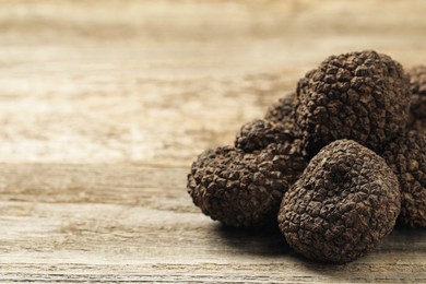 Heap of black truffles on wooden table, closeup. space for text