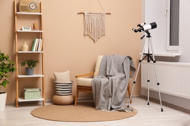 Photo of Tripod with modern telescope in stylish room