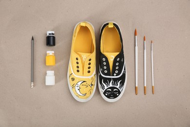 Photo of Amazing customized shoes and painting supplies on beige background, flat lay