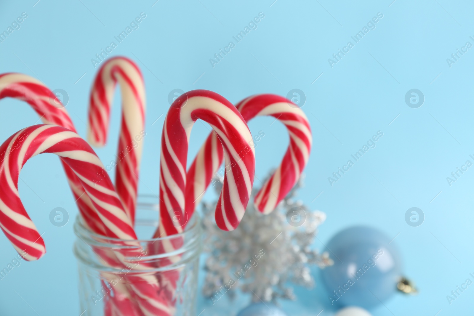 Photo of Christmas candy canes on light blue background, closeup. Space for text