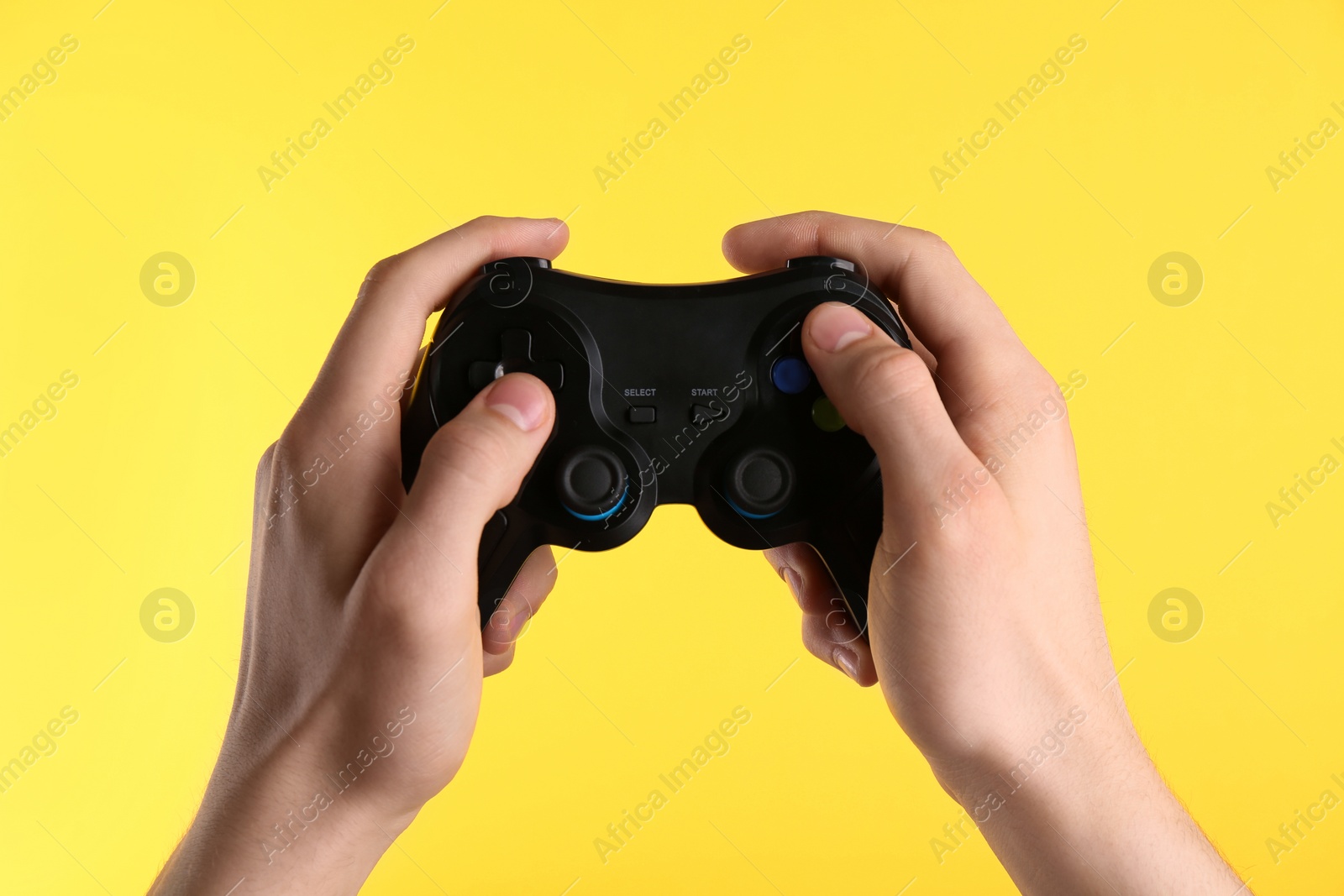 Photo of Man using wireless game controller on yellow background, closeup