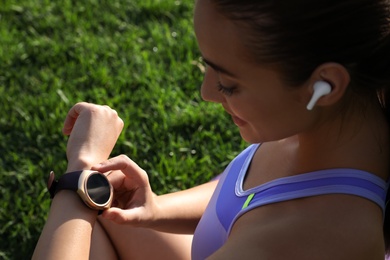 Photo of Woman checking fitness tracker after training in park, closeup