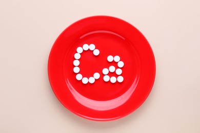 Photo of Plate with calcium symbol made of white pills on beige background, top view