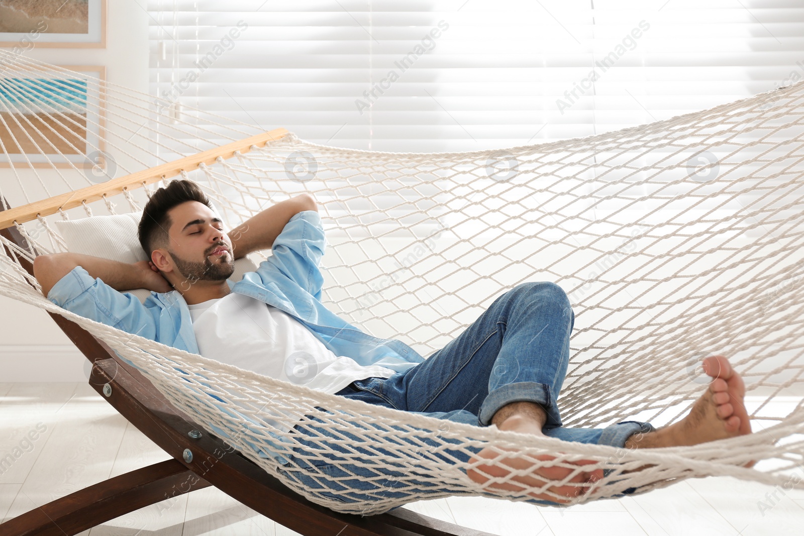 Photo of Young man relaxing in hammock at home