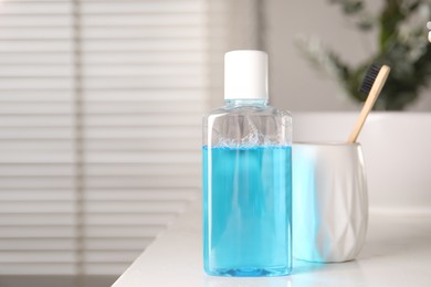 Bottle of mouthwash and toothbrush on white countertop in bathroom, space for text