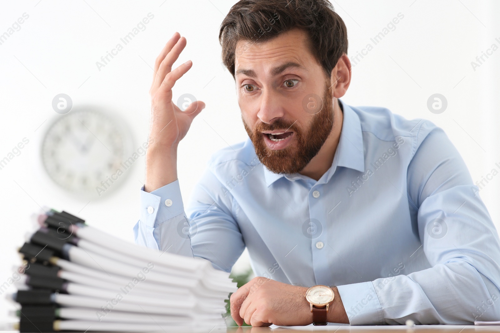 Photo of Emotional businessman with documents at wooden table in office