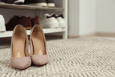 Photo of Orthopedic insoles in high heel shoes on rug. Space for text