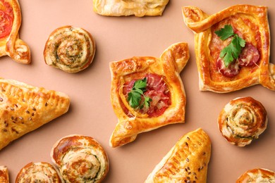 Different delicious puff pastry with tasty filling on beige background, flat lay