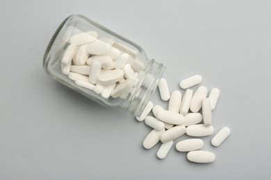 Vitamin pills and bottle on grey background, top view