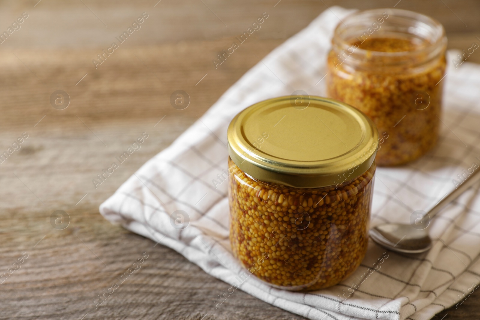 Photo of Jars of whole grain mustard on wooden table. Space for text