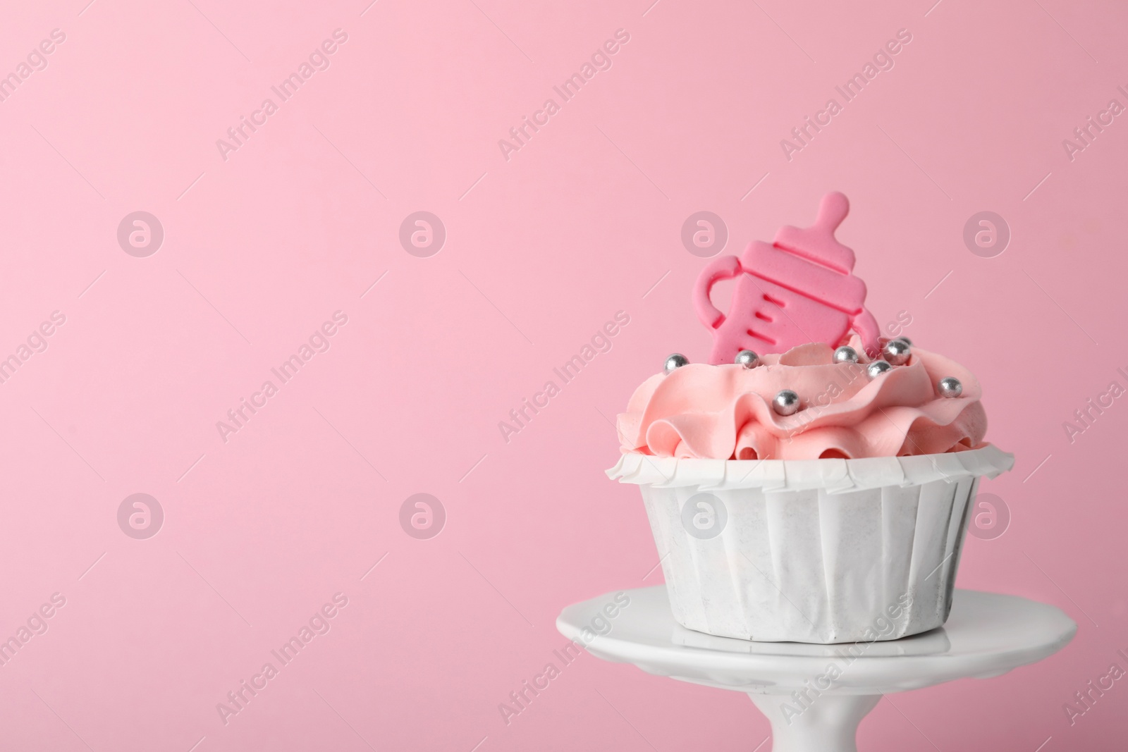 Photo of Baby shower cupcake with topper on pink background, closeup. Space for text