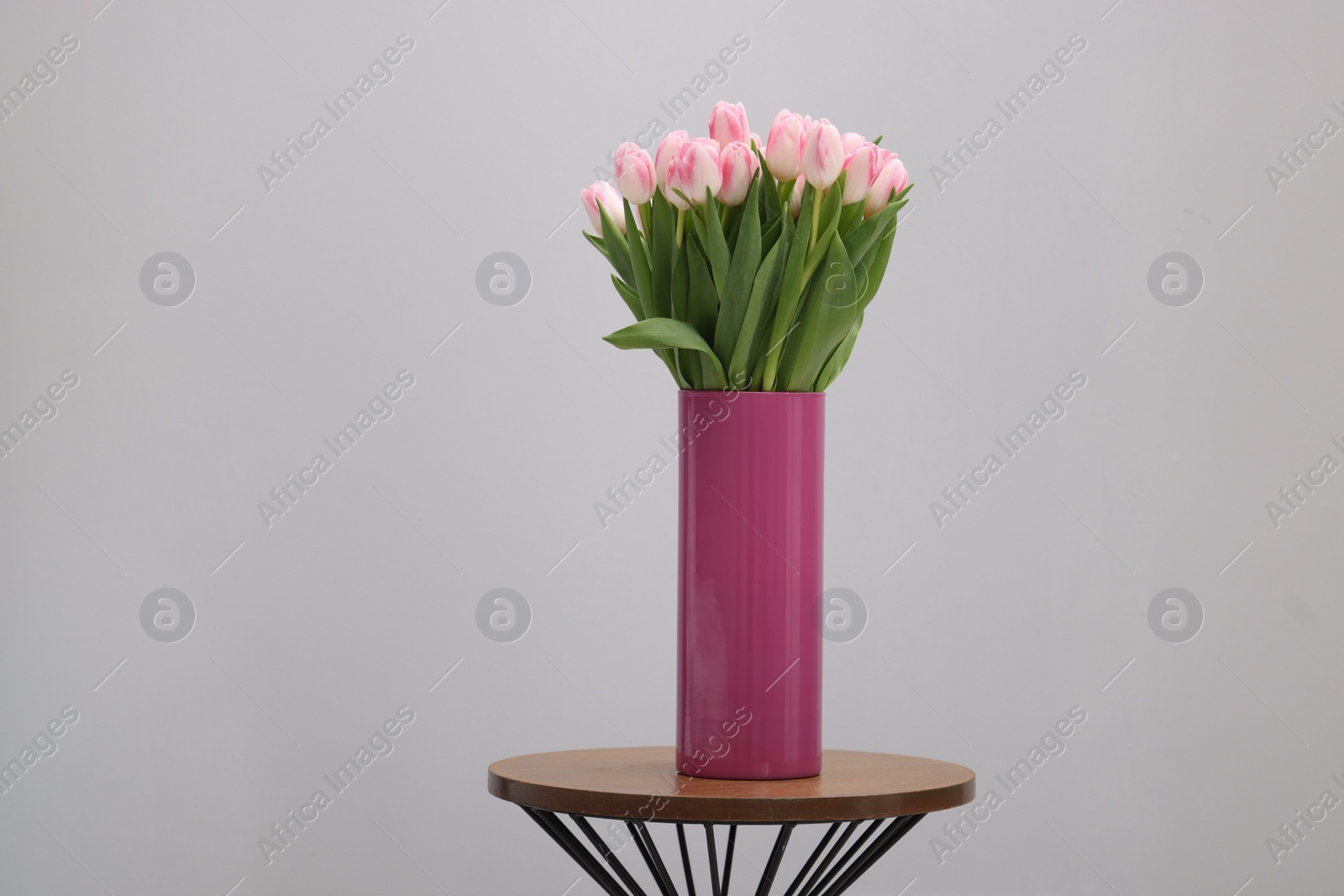 Photo of Beautiful bouquet of fresh pink tulips on table against light grey background