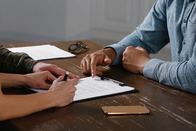 Photo of Notary working with couple at wooden table, closeup