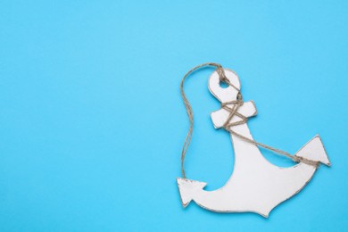 Photo of White wooden anchor figure on light blue background, top view. Space for text