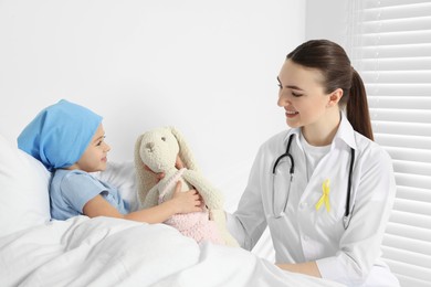 Photo of Childhood cancer. Doctor and little patient with toy bunny in hospital