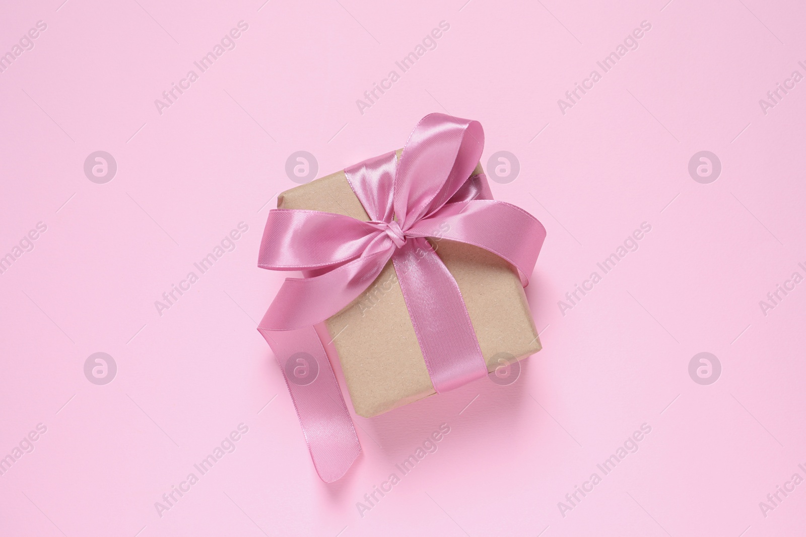 Photo of Beautiful gift box with bow on pink background, top view