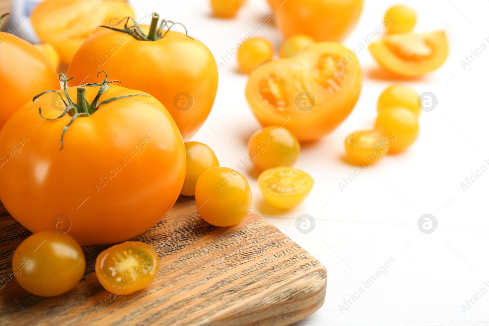 Photo of Ripe yellow tomatoes on white wooden table, closeup