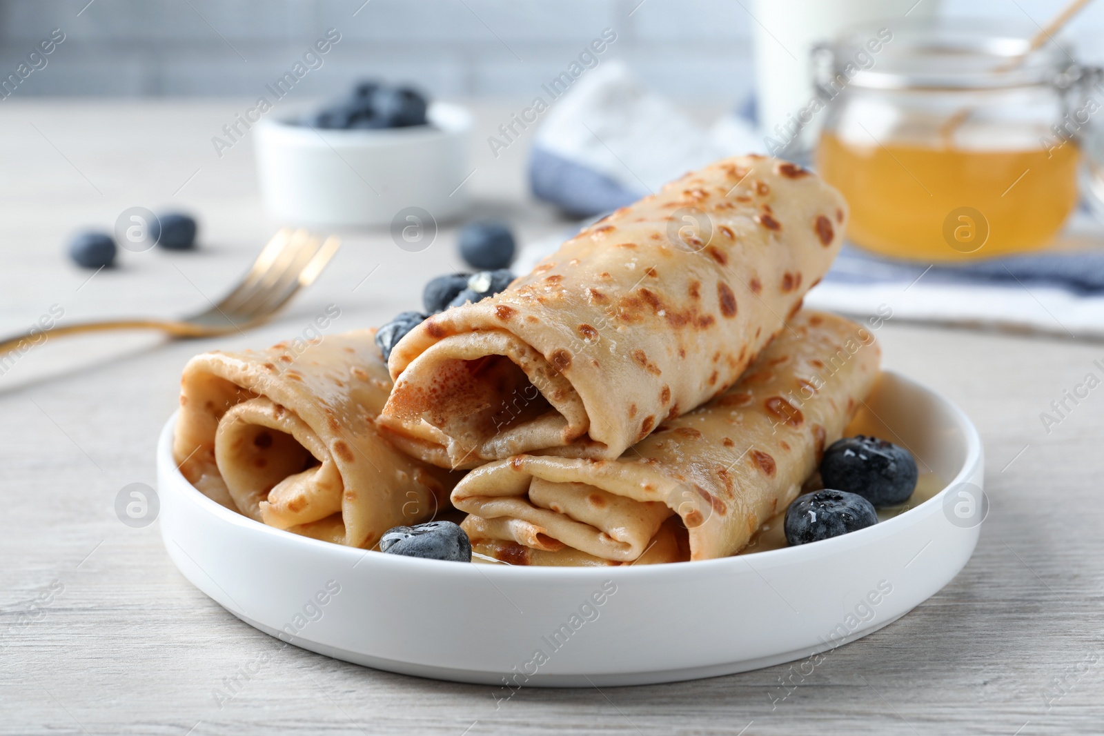 Photo of Delicious crepes with blueberries on white wooden table, closeup