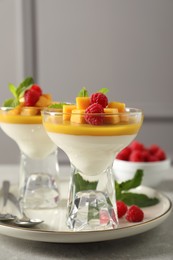 Photo of Delicious panna cotta with mango and raspberries on grey table