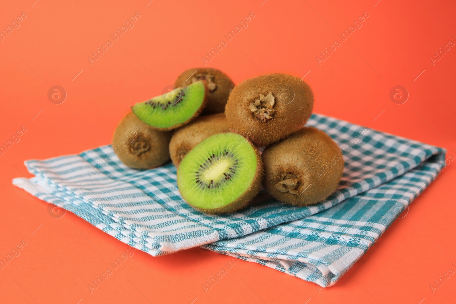 Photo of Heap of whole and cut fresh kiwis on orange background