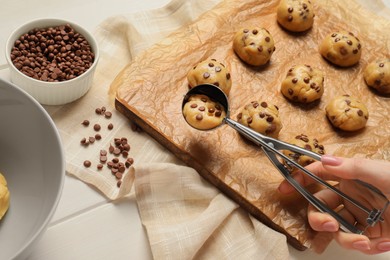 Photo of Woman making delicious chocolate chip cookies at white wooden table, closeup