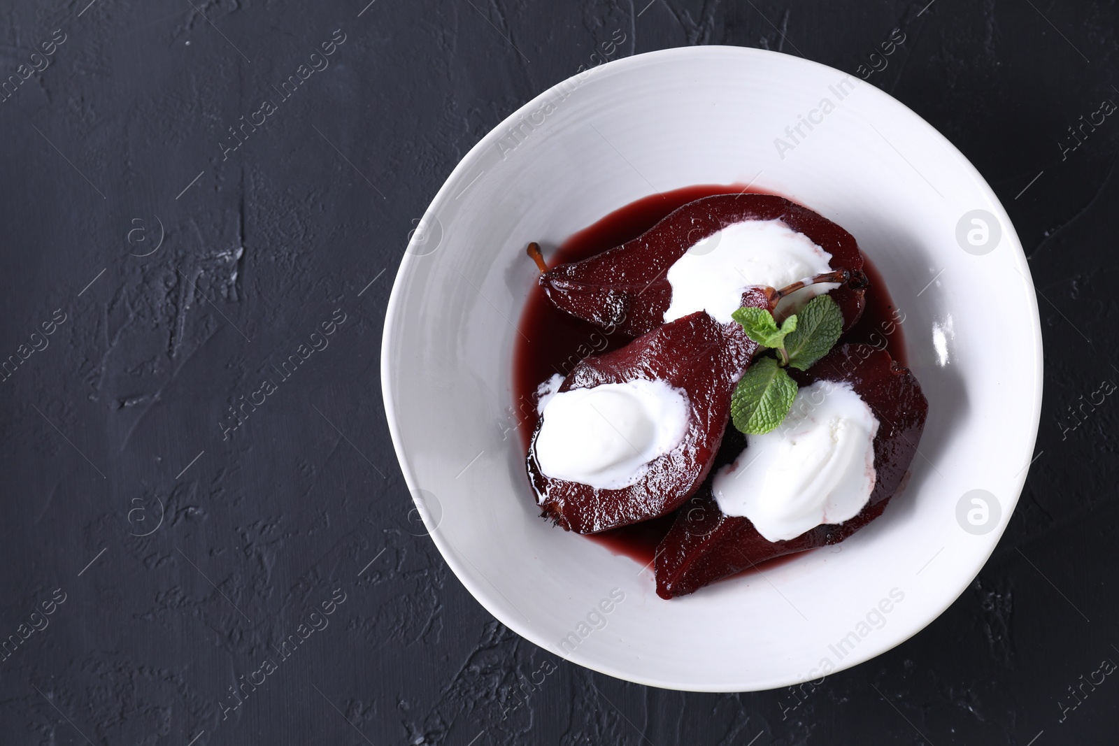 Photo of Tasty red wine poached pears, mint and ice cream on black table, top view. Space for text