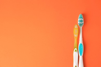 Photo of Toothbrushes on orange background, flat lay. Space for text