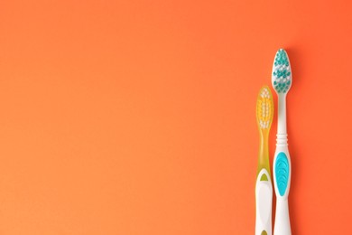 Toothbrushes on orange background, flat lay. Space for text