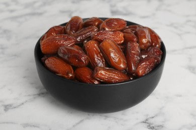 Photo of Sweet dried dates in bowl on white marble table