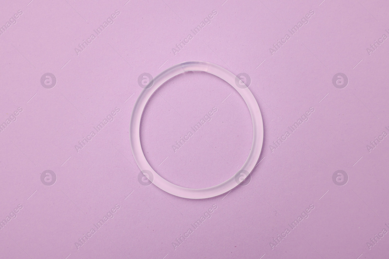 Photo of Diaphragm vaginal contraceptive ring on lilac background, top view