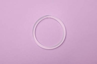 Photo of Diaphragm vaginal contraceptive ring on lilac background, top view