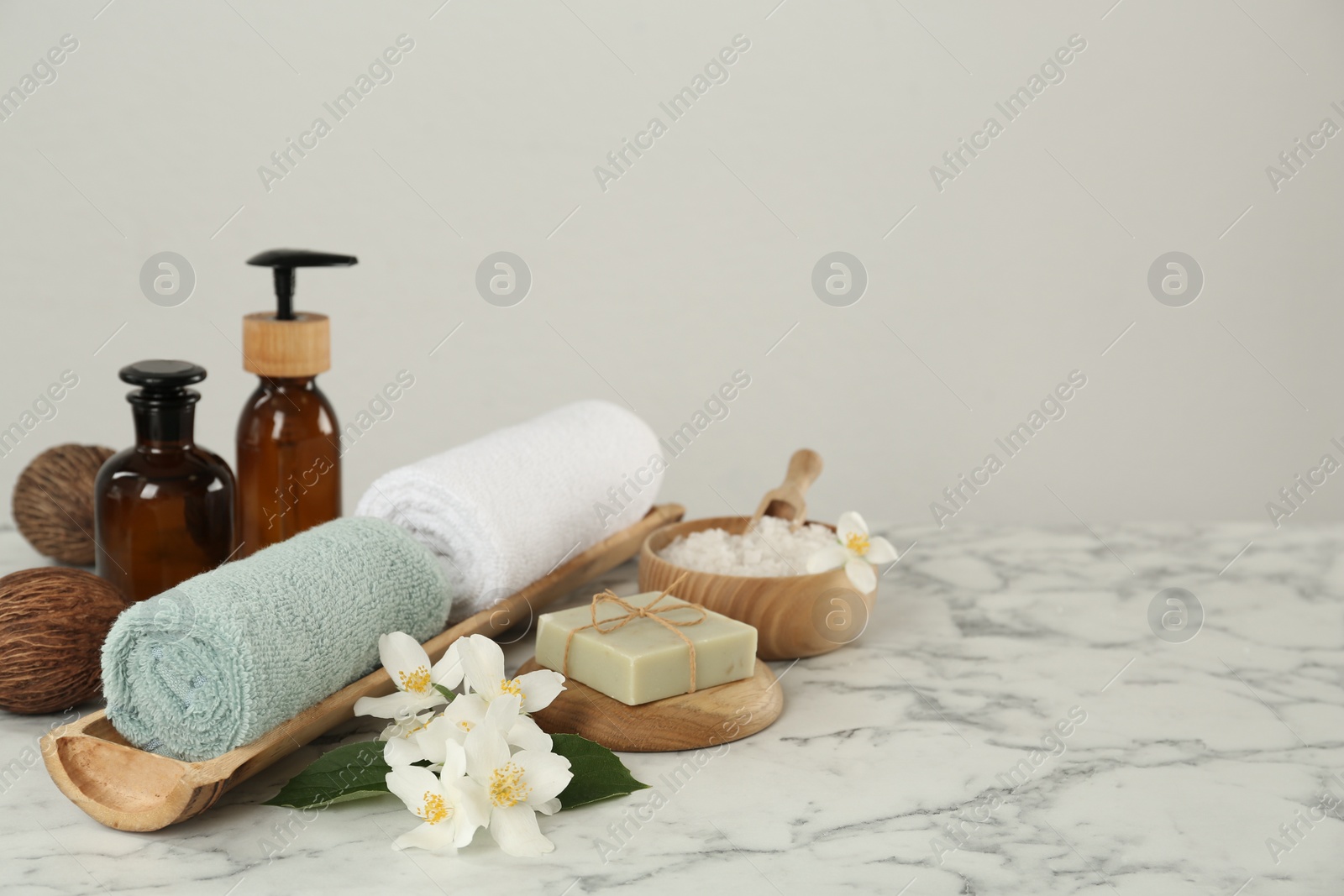 Photo of Composition with beautiful jasmine flowers and skin care products on white marble table, space for text