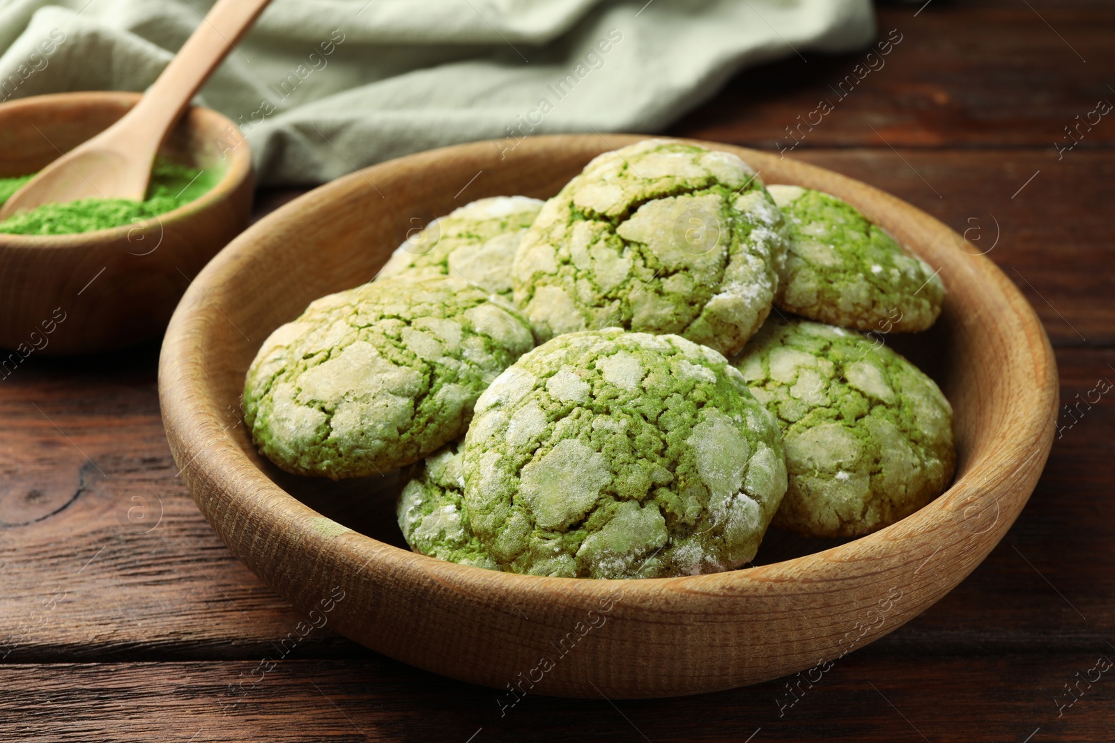 Photo of Bowl with tasty matcha cookies on wooden table, closeup