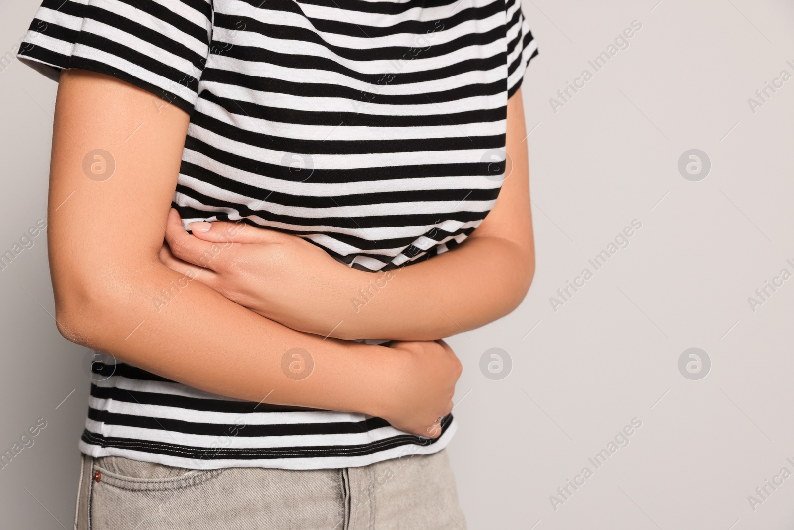 Photo of Young woman suffering from menstrual pain on grey background, closeup. Space for text