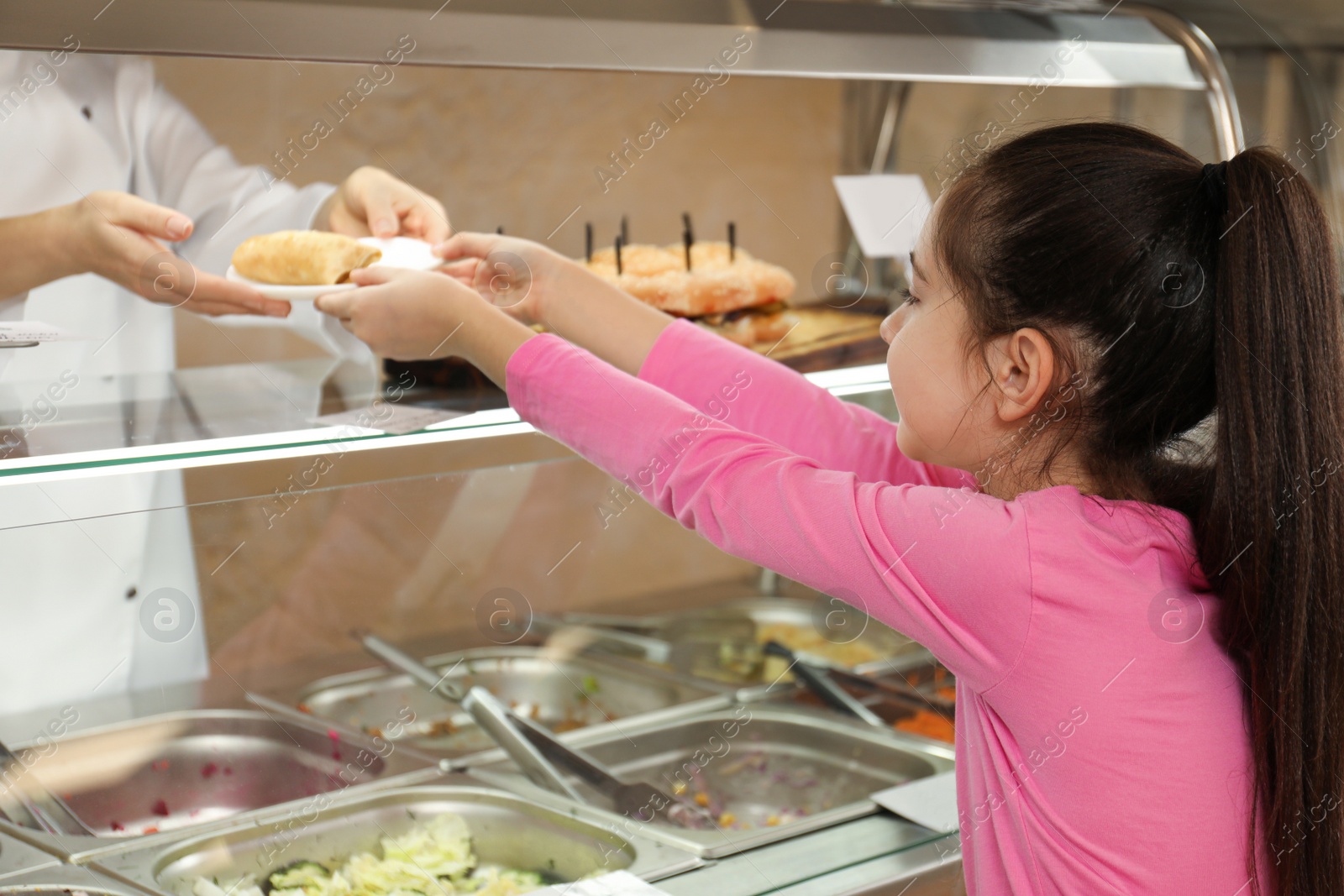 Photo of Woman giving plate with tasty food to girl in school canteen