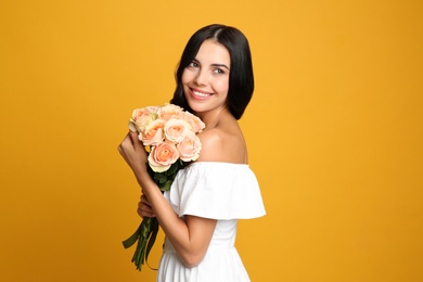 Photo of Portrait of smiling woman with beautiful bouquet on orange background