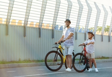 Dad and son riding bicycles at stadium