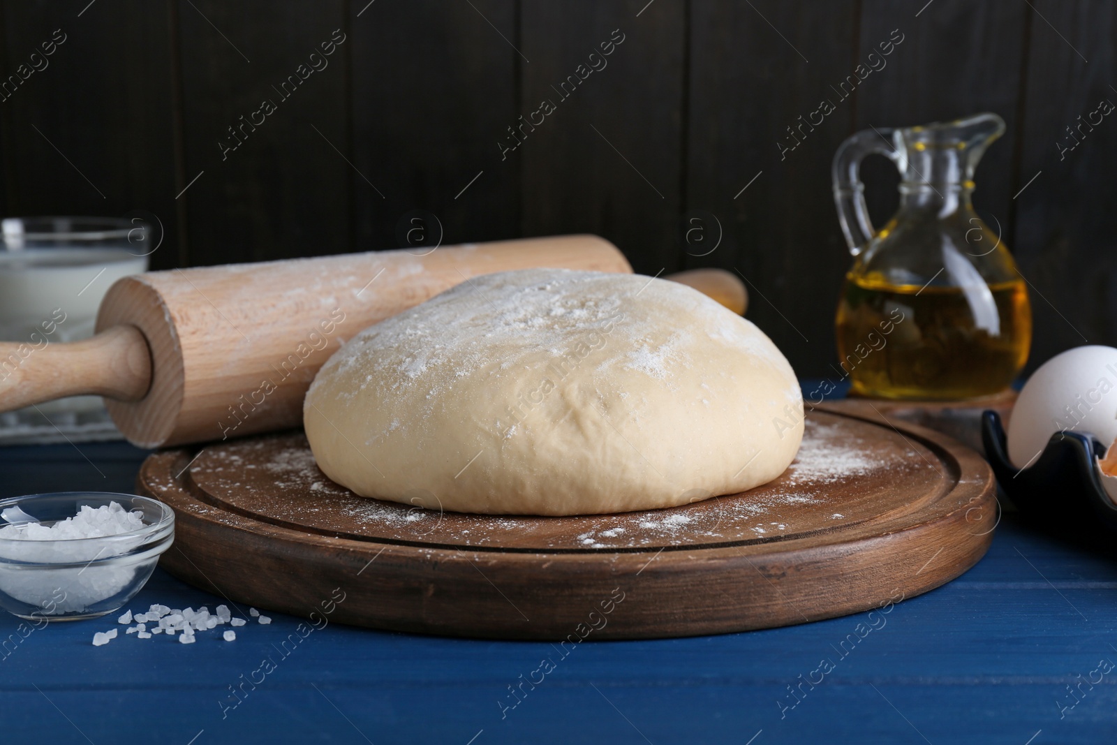 Photo of Fresh yeast dough and ingredients on blue wooden table