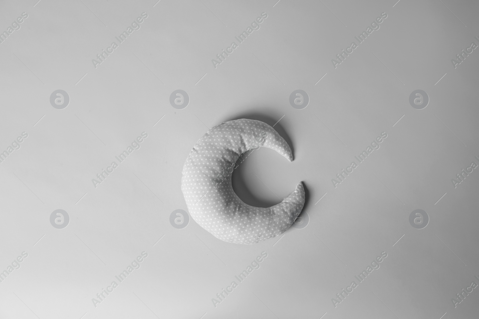 Photo of Soft pillow in shape of moon on light background