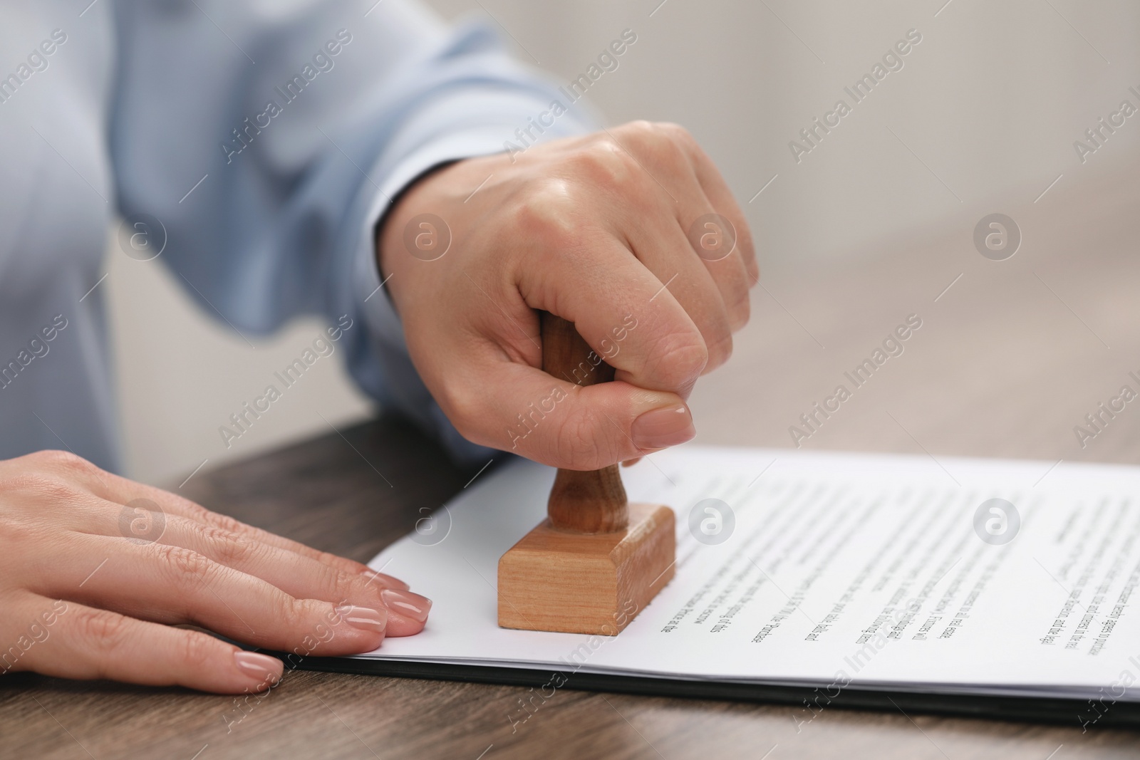 Photo of Woman stamping document at wooden table, closeup