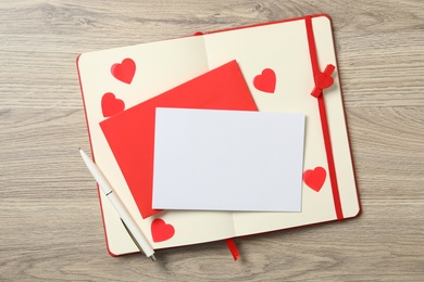 Photo of Blank card, envelope and notebook on wooden background, top view with space for text. Valentine's Day celebration