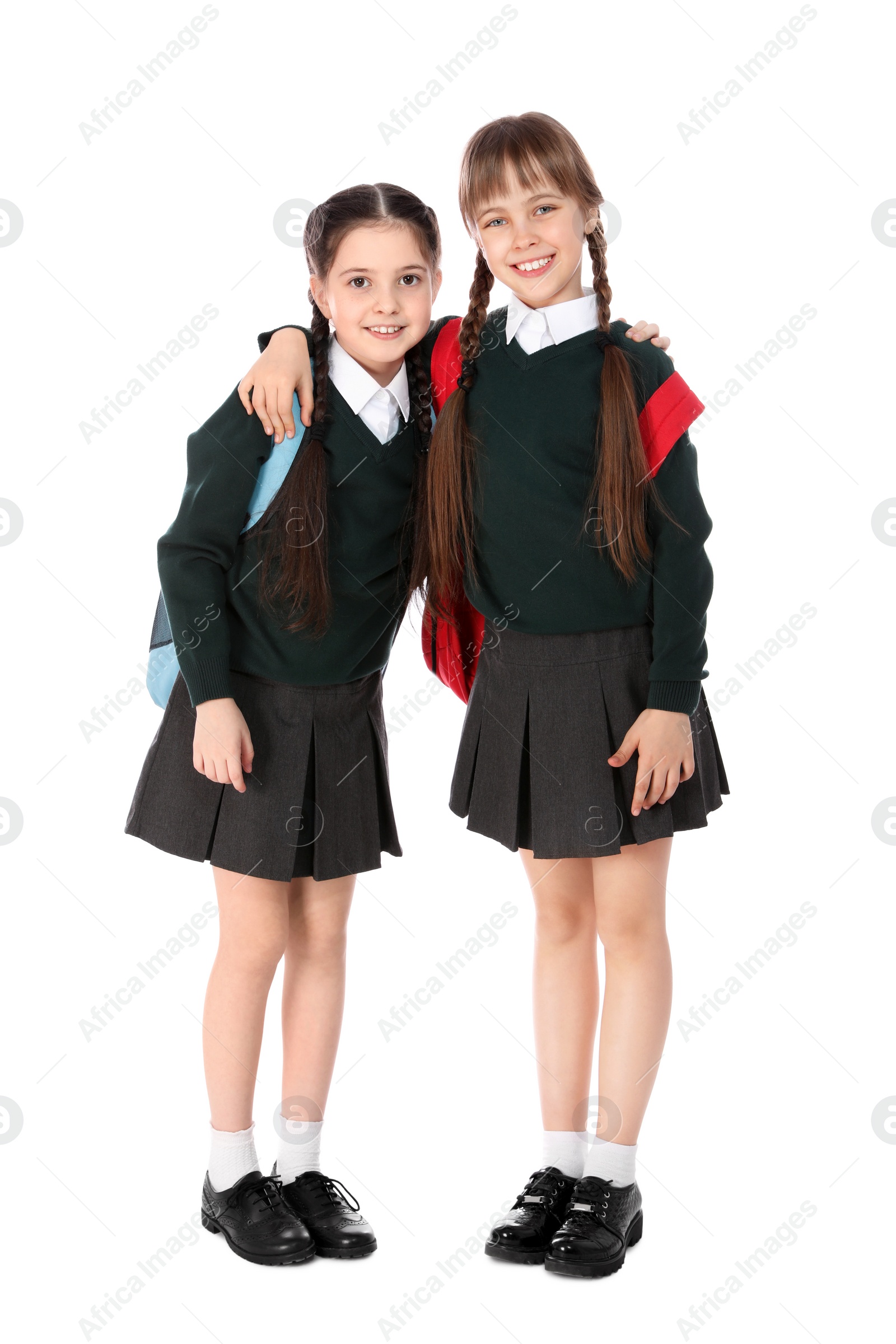 Photo of Full length portrait of cute girls in school uniform with backpacks on white background